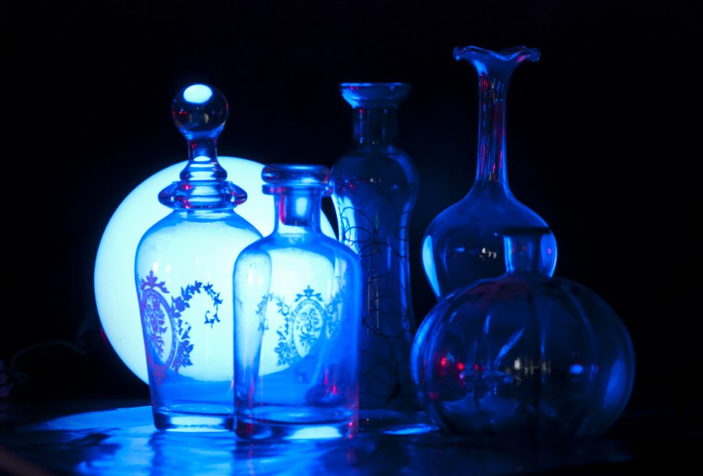 A set of empty vials sit against a blue backlight